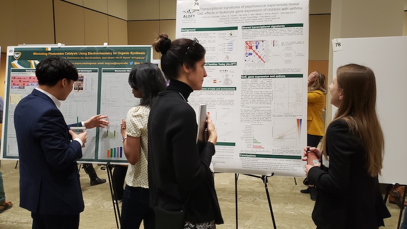 two women chatting in front of research poster
