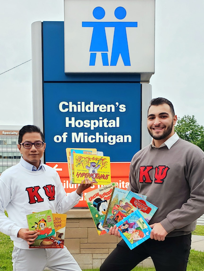 Kappa Psi brothers Joseph Paul Javier and Hussein Safaoui at the DMC Children's Hospital, one of Reach Out and Read's local sites.