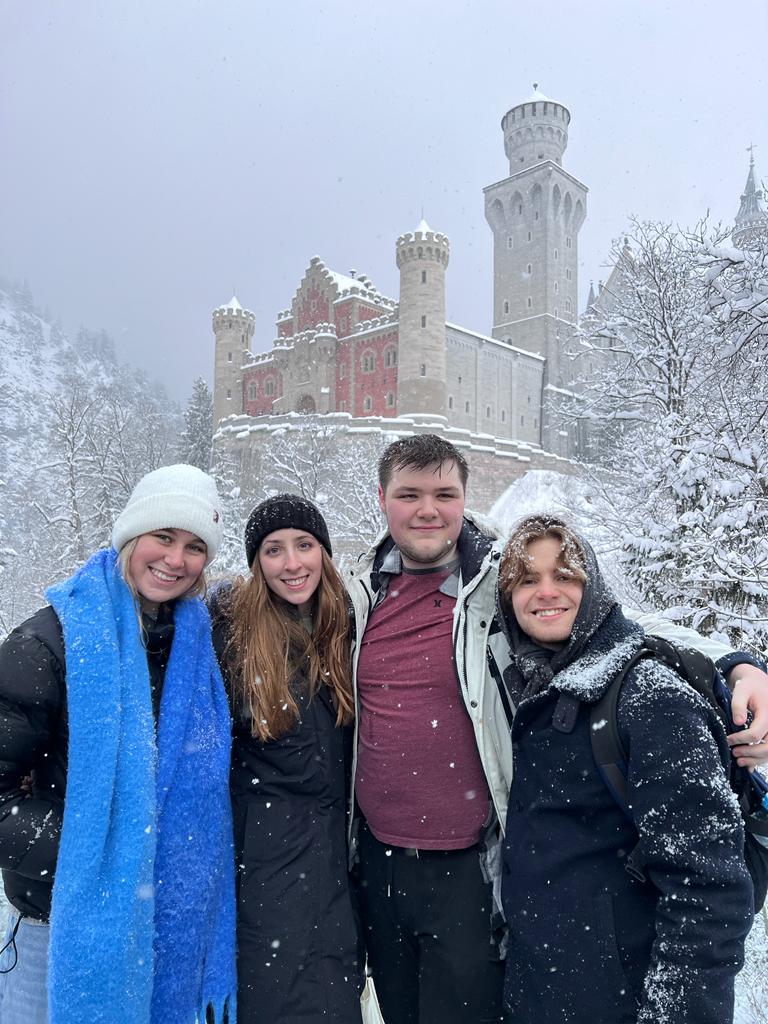 Junior Year in Munich students stand in front of the Neuschwanstein Castle in winter 2023 as part of a culture class.
