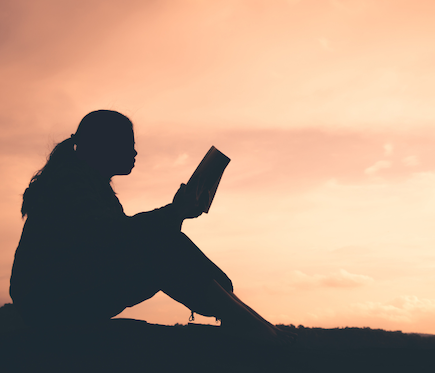 woman reading book at sunset