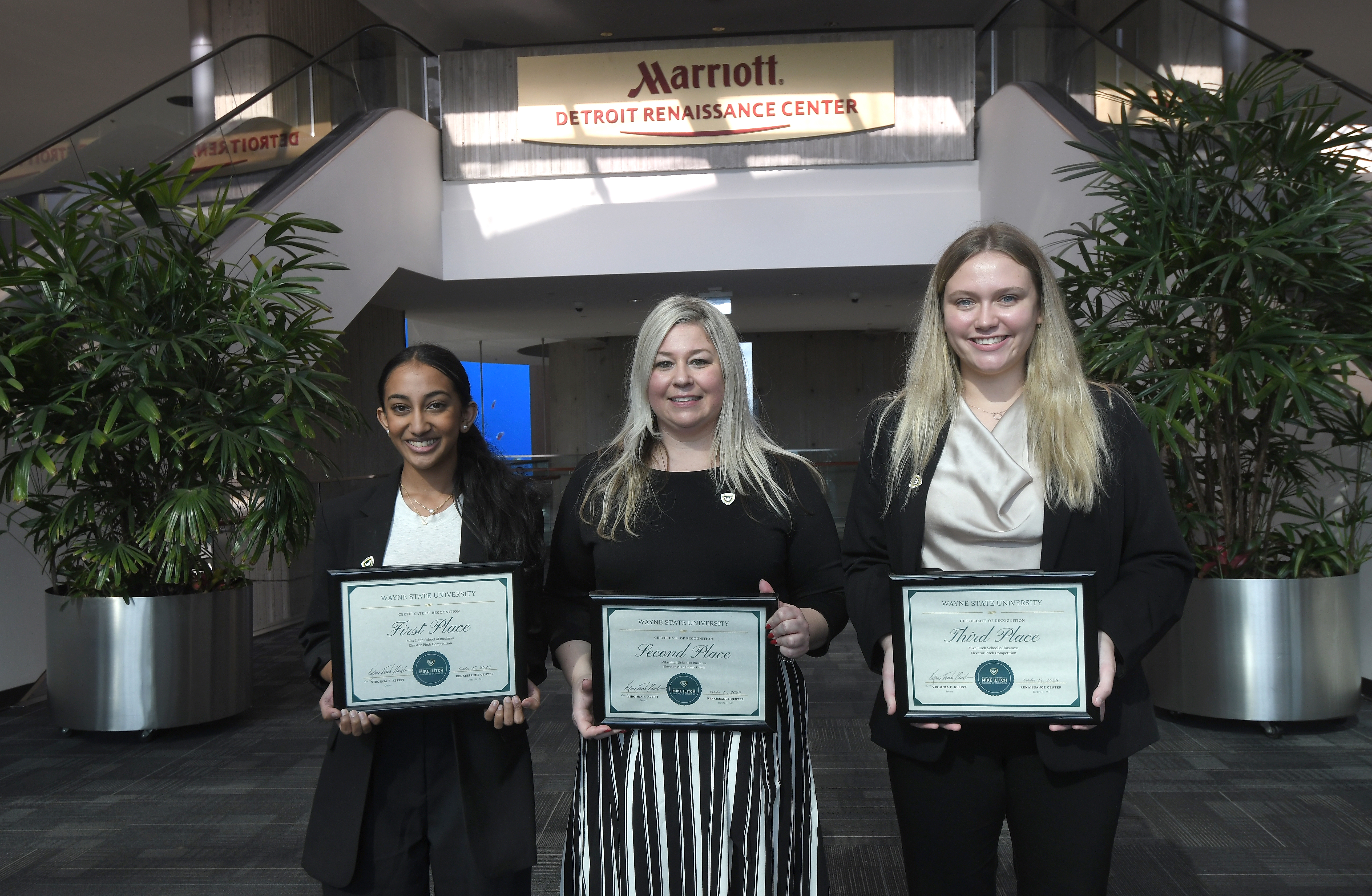 Three women holding plaques next to each other.