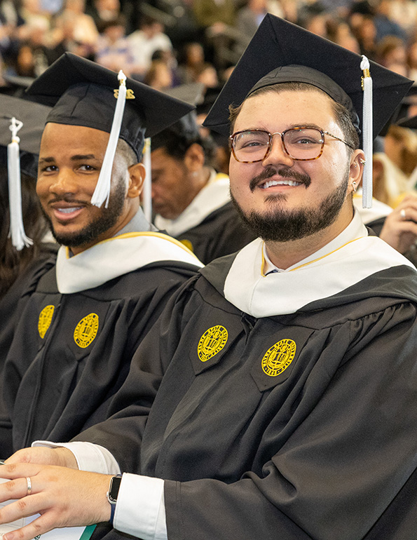 Two male graduates smile for the camera during the spring 2023 commencements.