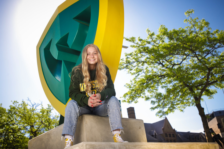 A Wayne State student poses for a photo by the giant W