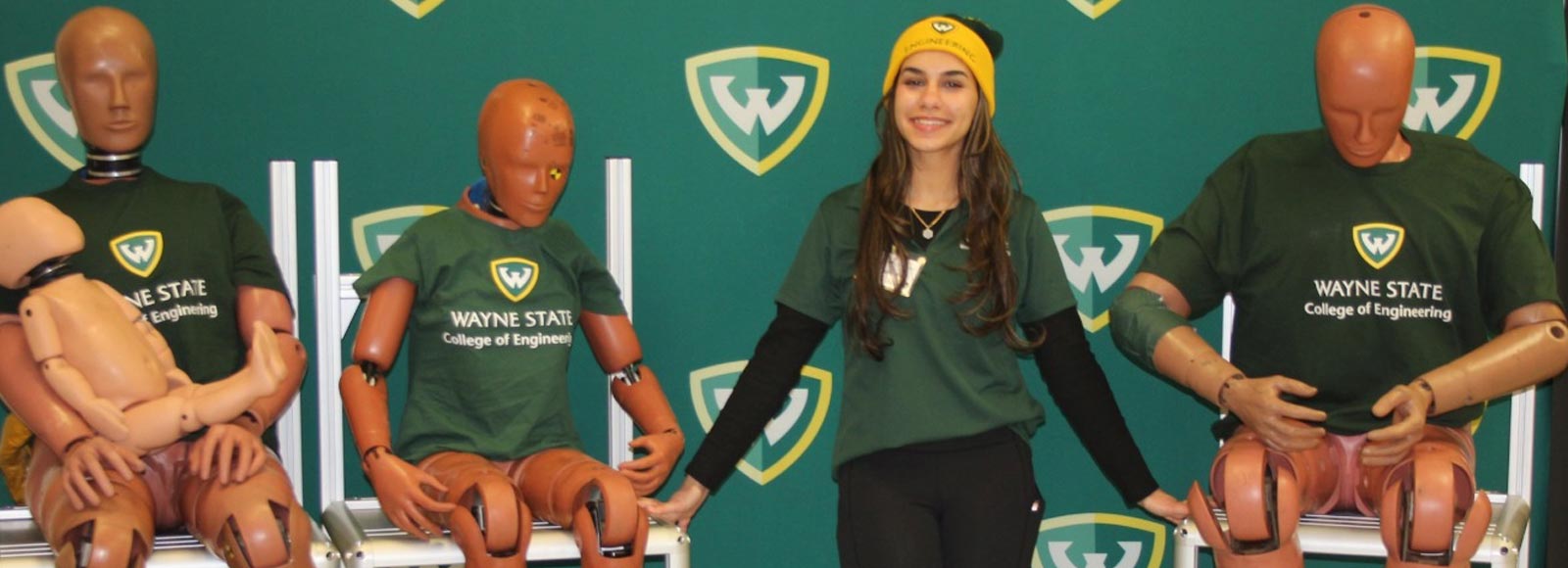Wayne State BME student Maryam Adel posing for a photo with a set of crash test dummies