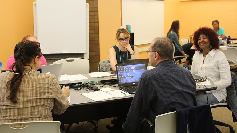 A group of faculty and staff work together in the library.