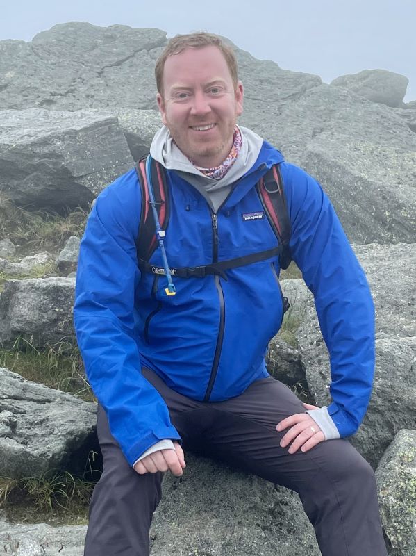 O'Leary sits outside while on rocks with a foggy sky 