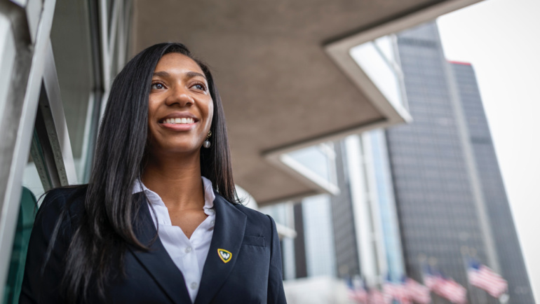 A smiling intern stands outside an office building in Detroit