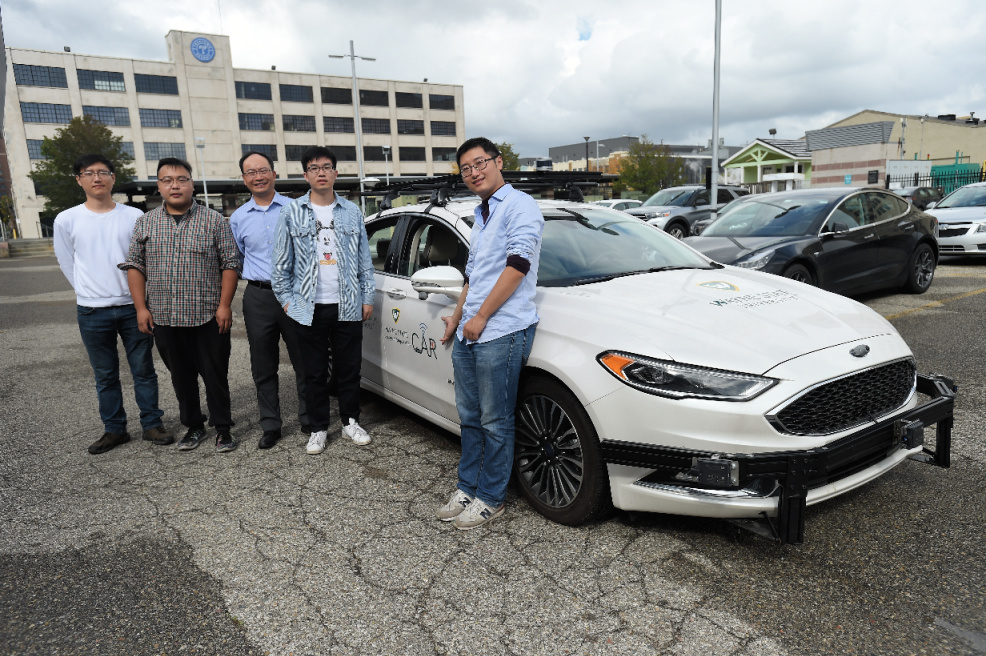 Researchers at the CAR Lab pose with their autonomous vehicle.