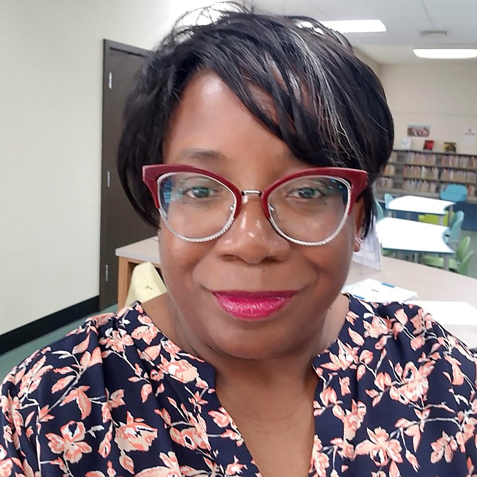 A headshot of School of Information Sciences alumna Christine Peele. She is a Black woman with short hair. Her bangs sweep across her forehead and she is wearing red cat-eye framed glasses and bright pink lipstick.