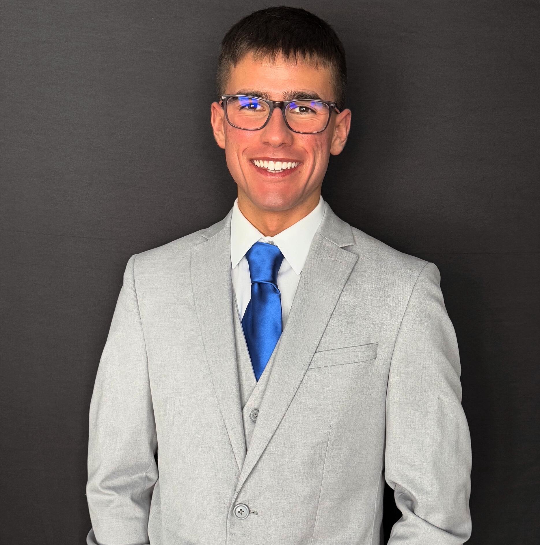 Cody Bannick poses in a suit, smiling at camera