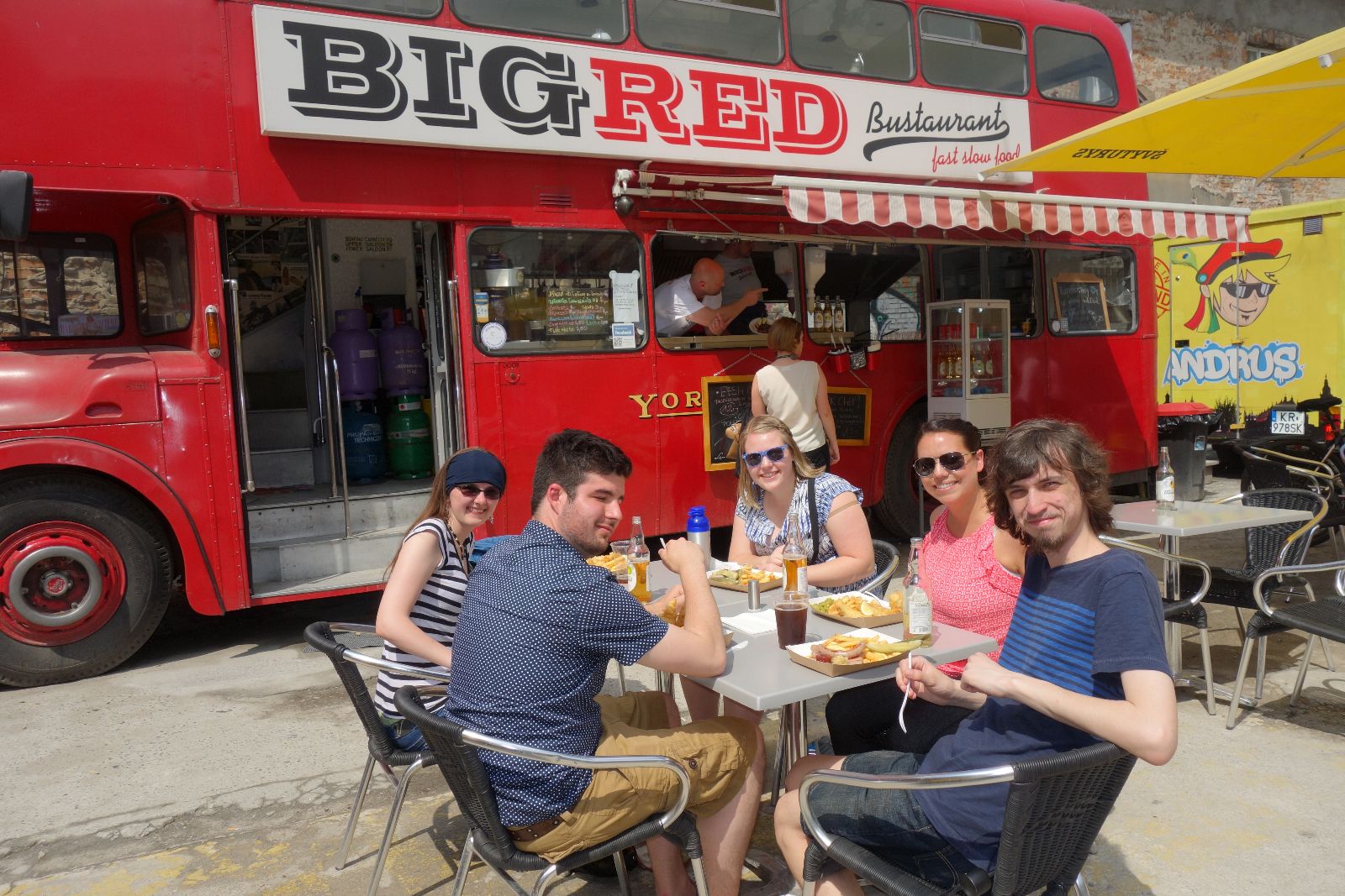 People sitting at a table eating in front of a food truck