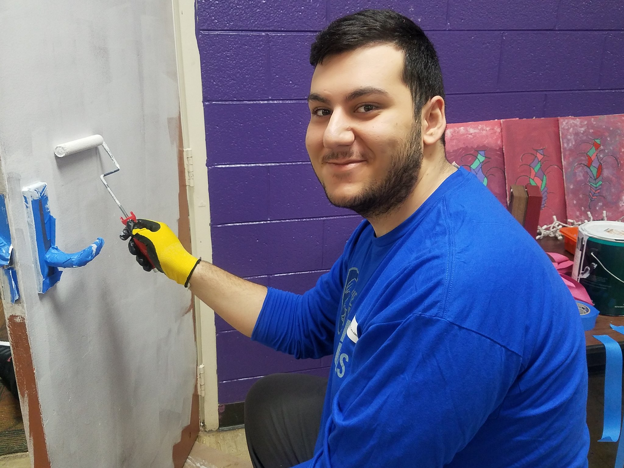 Faris Alkhouri smiling while painting a door white