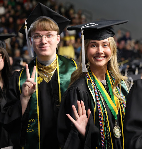 Graduates wave at the camera.