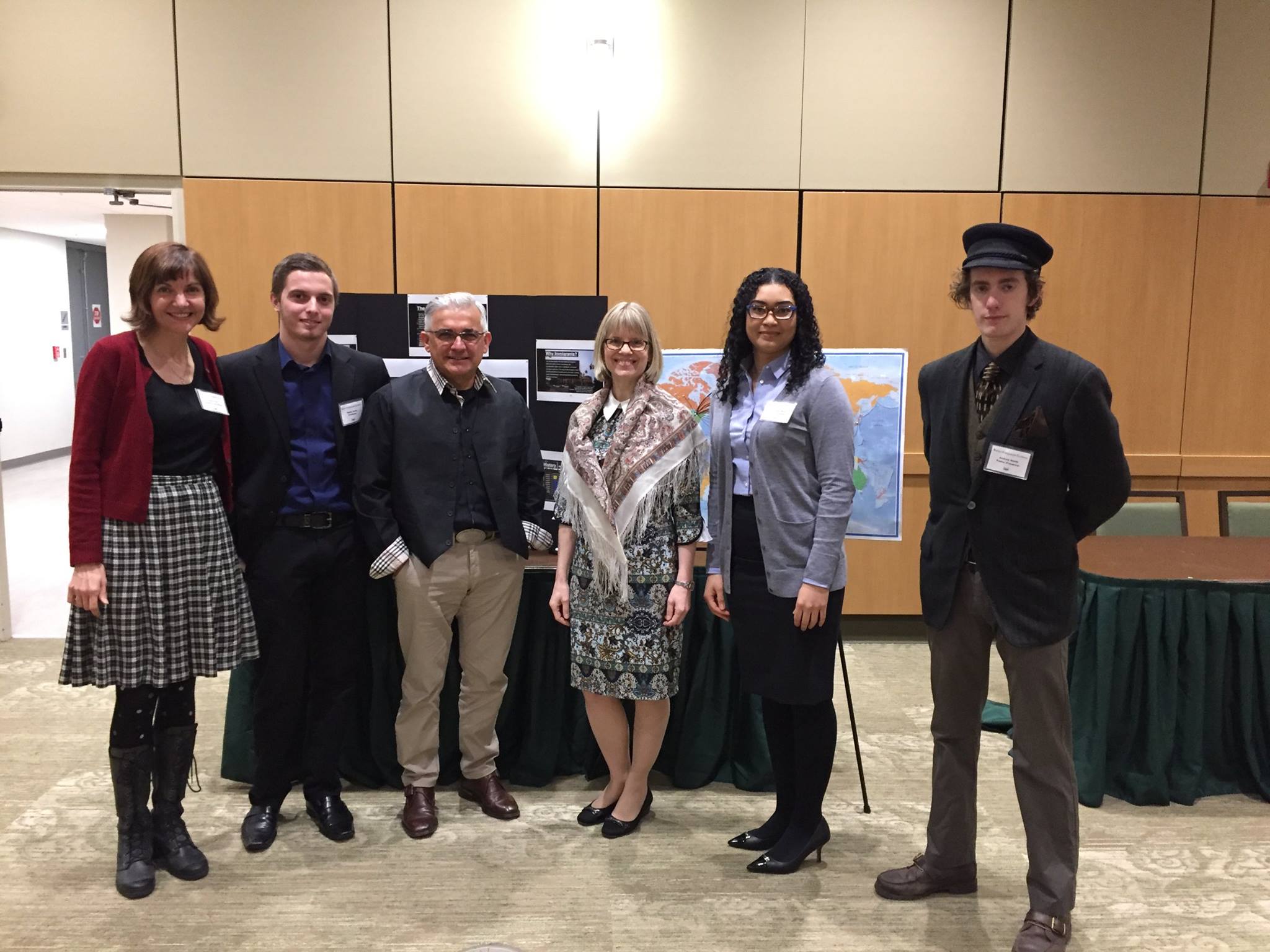 Six students and faculty standing in front of a display