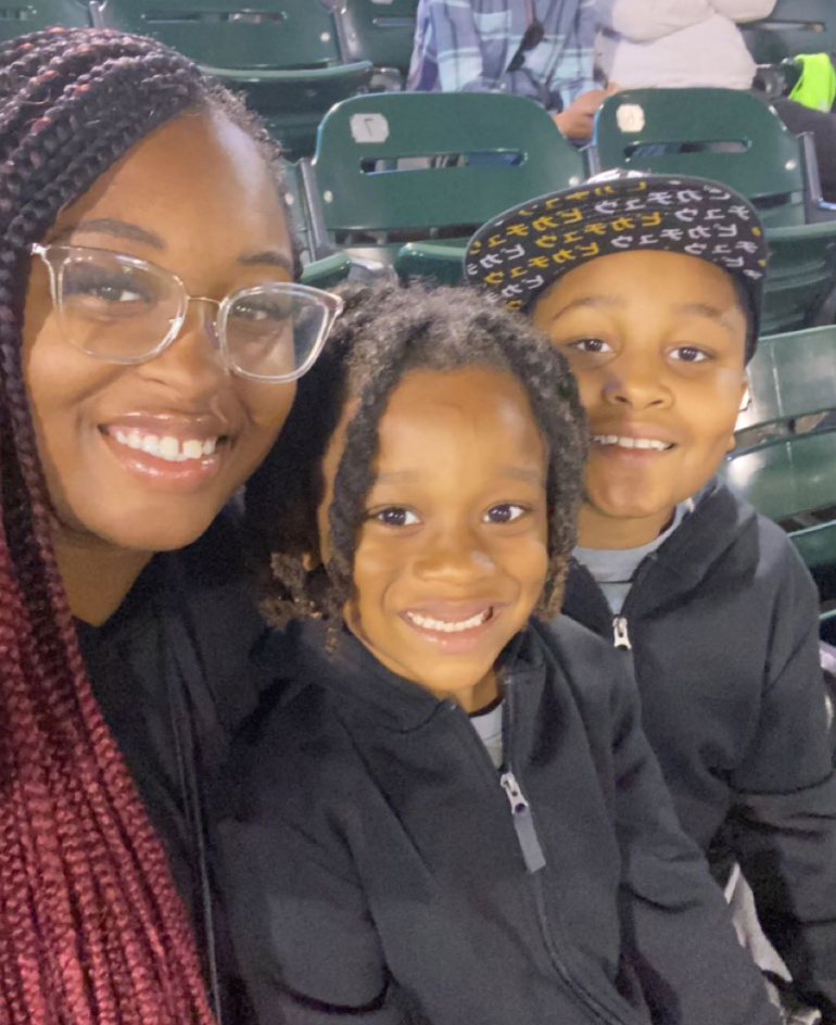 Francis-Brown sits at a baseball game with her two children.