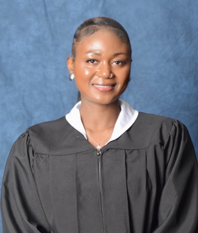 BSN graduate Nennie Sheriff smiles for a photo wearing a black graduation gown.