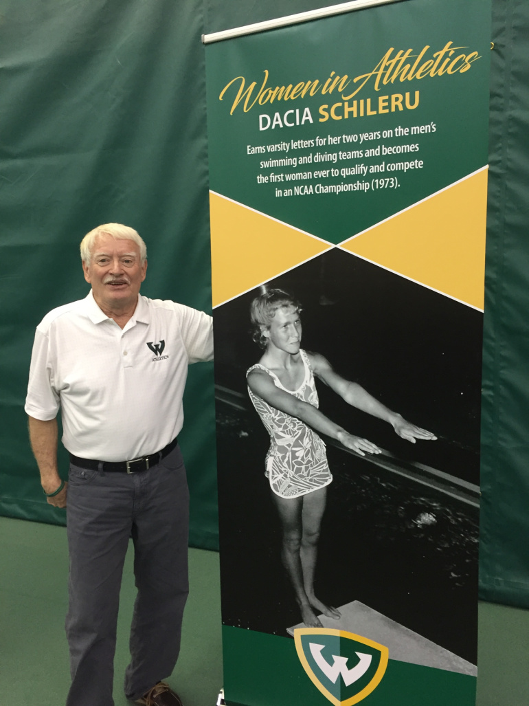 Peter Roberts stands by a banner for Wayne State diver Dacia Schileru.