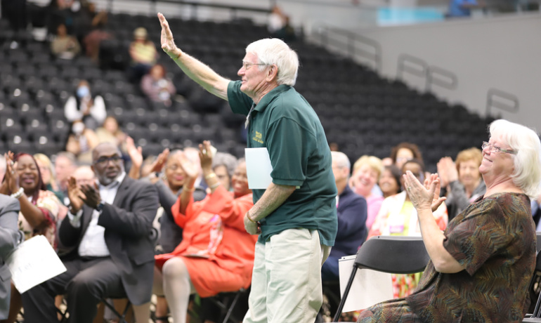 Peter Roberts waves to the crowd at the Employee Recognition Ceremony as he is acknowledged for being at Wayne State more than 50 years.