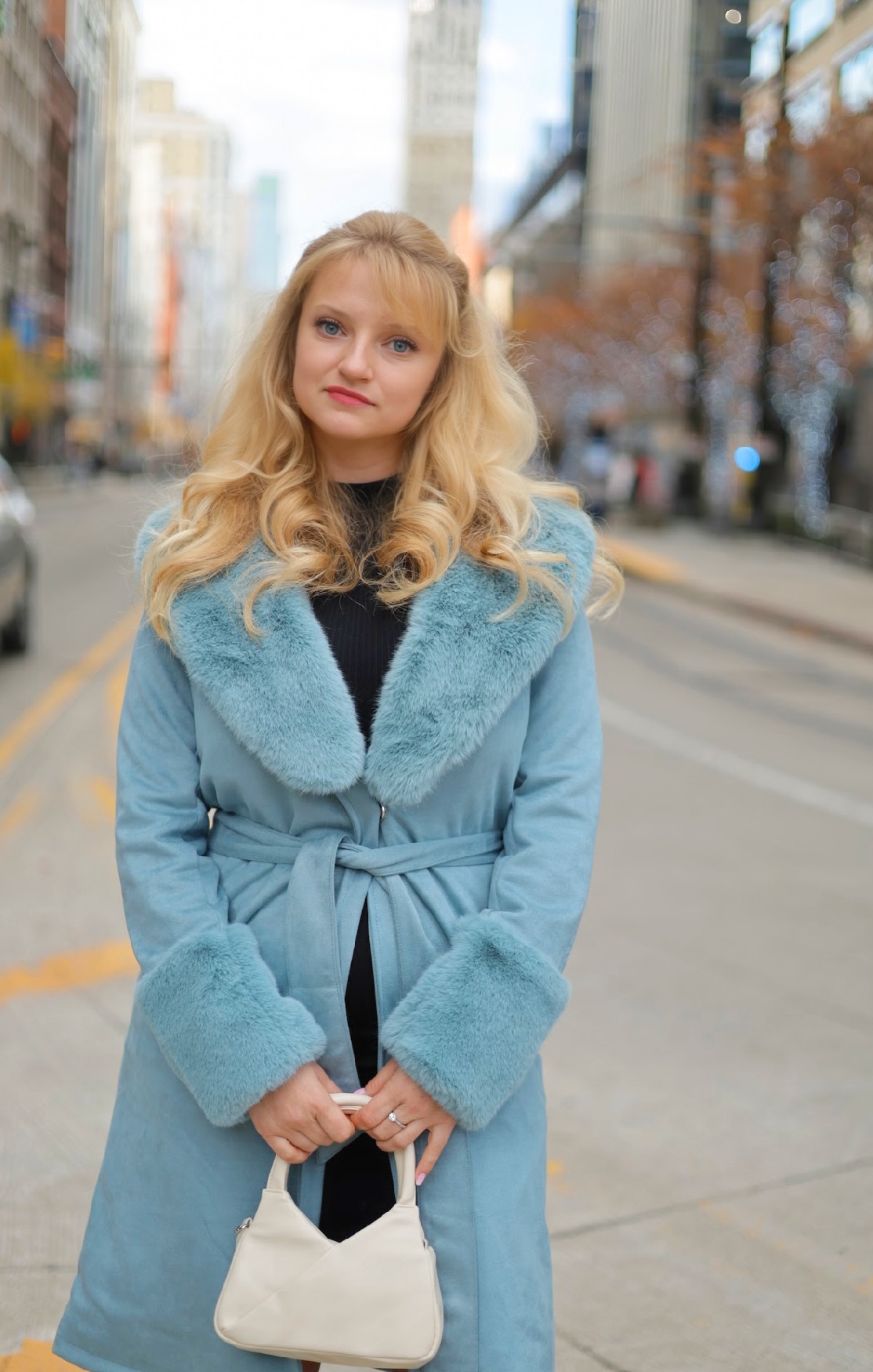 Student Iryna Hatala wearing a blue coat and carrying a small white bag