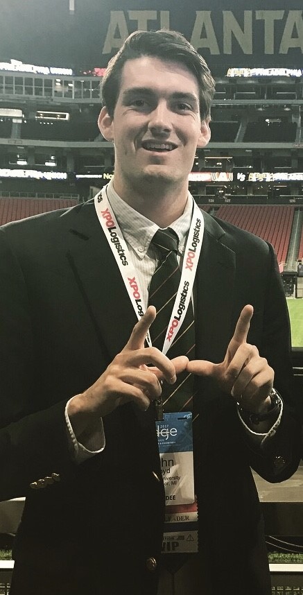 John Floyd standing in stadium giving WSU W sign with fingers while attending conference in Atlanta