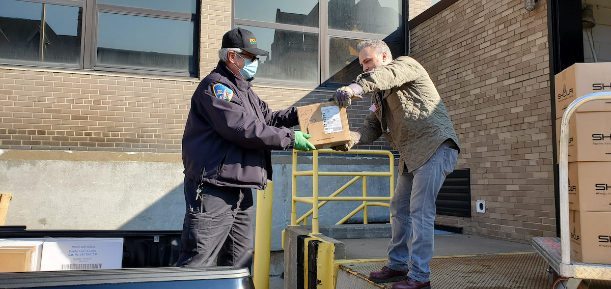 Storeskeeper Jason Parizon hands off PPE to the Wayne State Police