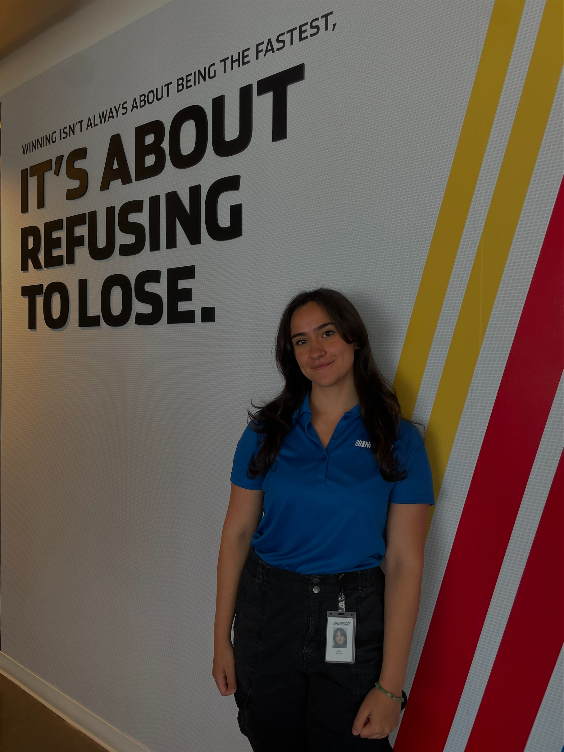 Woman standing in front of wall saying Winning isn't about being the fastest, it's about refusing to lose.