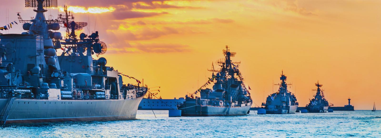 Warships in ocean, heading toward sunset