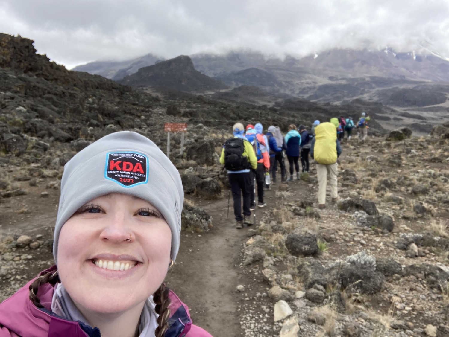 WSU student Emily Polet-Monterosso takes a selfie during the climb up Mount Kilimanjaro. Her smiling face is in the foreground and we can see several other climbers behind her.