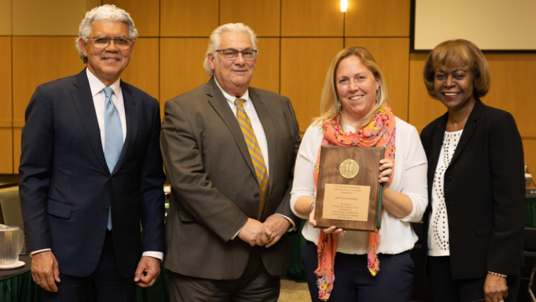 Krysta Ryzewski (second from right) holds up her award next to Wayne State President M. Roy Wilson (left) and two members of the Board of Governors.
