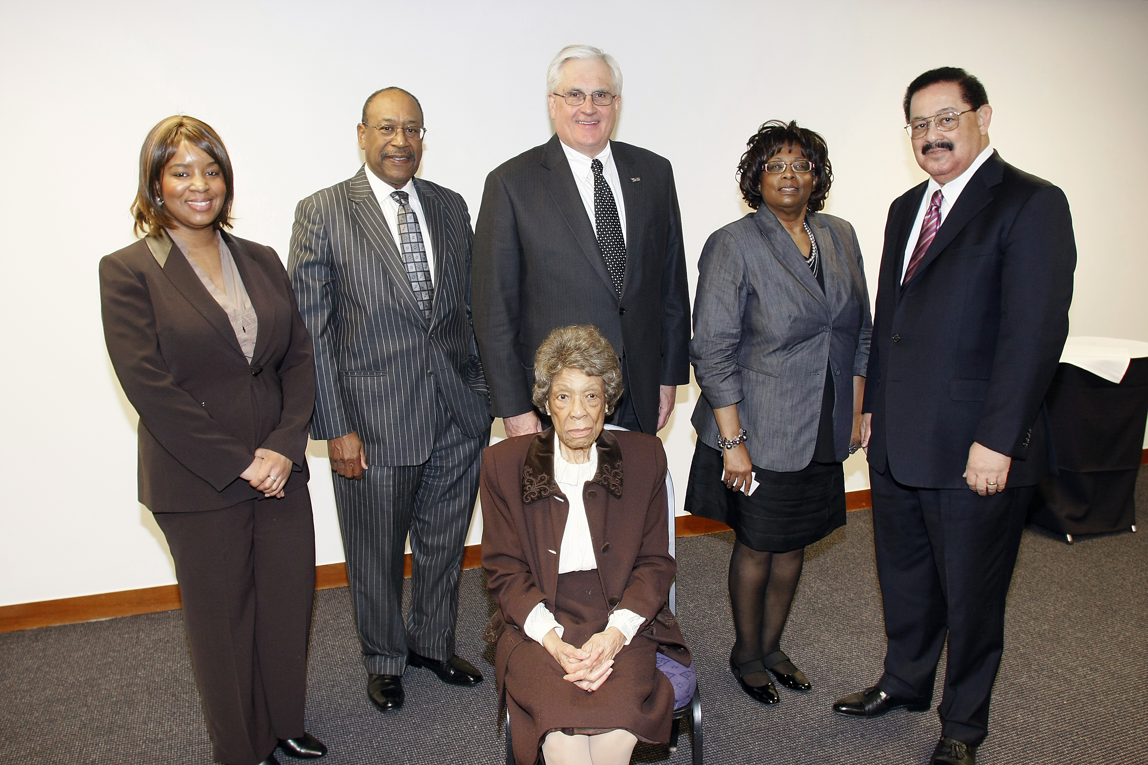 Five people standing around one seated person.