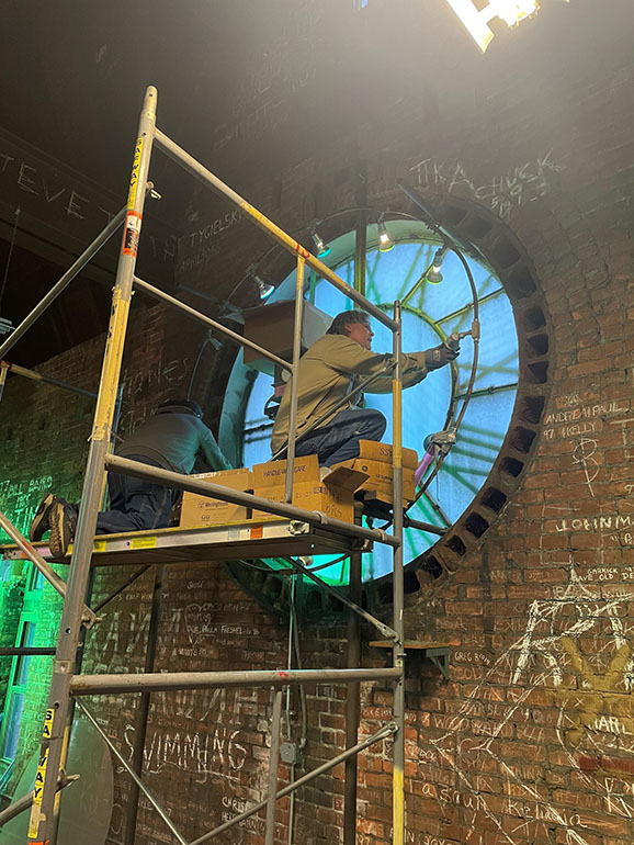 An electrician changes the lights on one Old Main’s four clock faces.