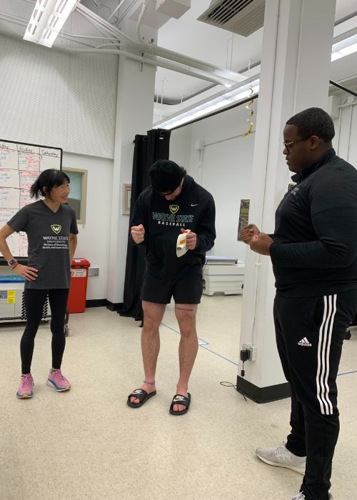 Hew-Butler and Grove watch a student-athlete complete the handgrip test