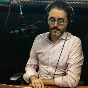 Man in front of radio microphone in studio.