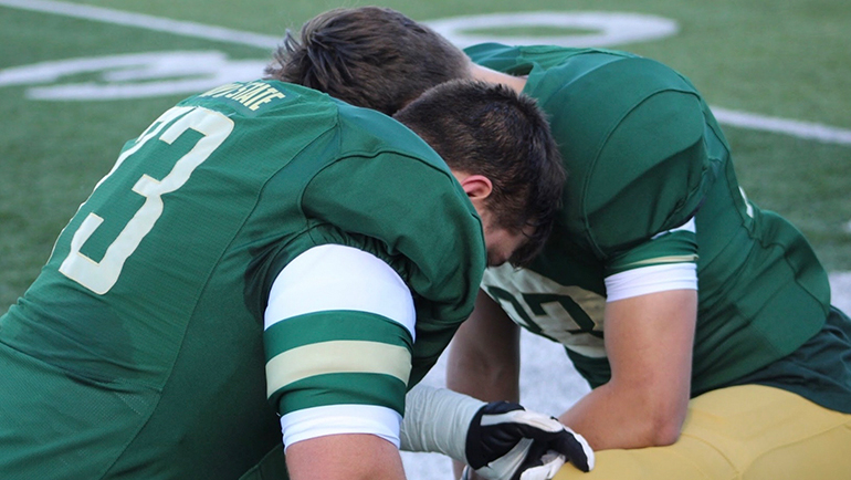 Teammates since high school, Noah Nicklin (left) and his brother Max Nicklin share a moment together prior to the start of a Wayne State football game.