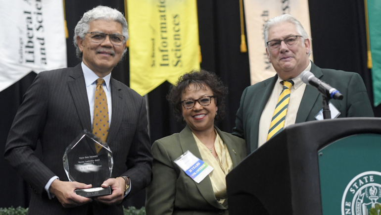 President M. Roy Wilson (left) holds up an award as he poses for a photo with board of governors member Mark Gaffney and Associate Vice President and Chief Human Resources Officer Carolyn Hafner.