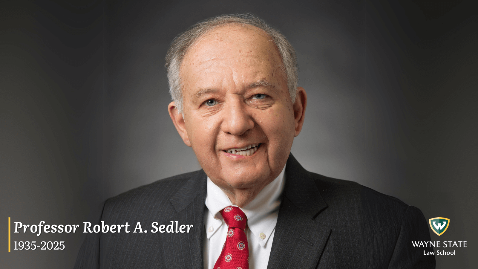 Robert Sedler pictured wearing a dark suit, white shirt and red tie