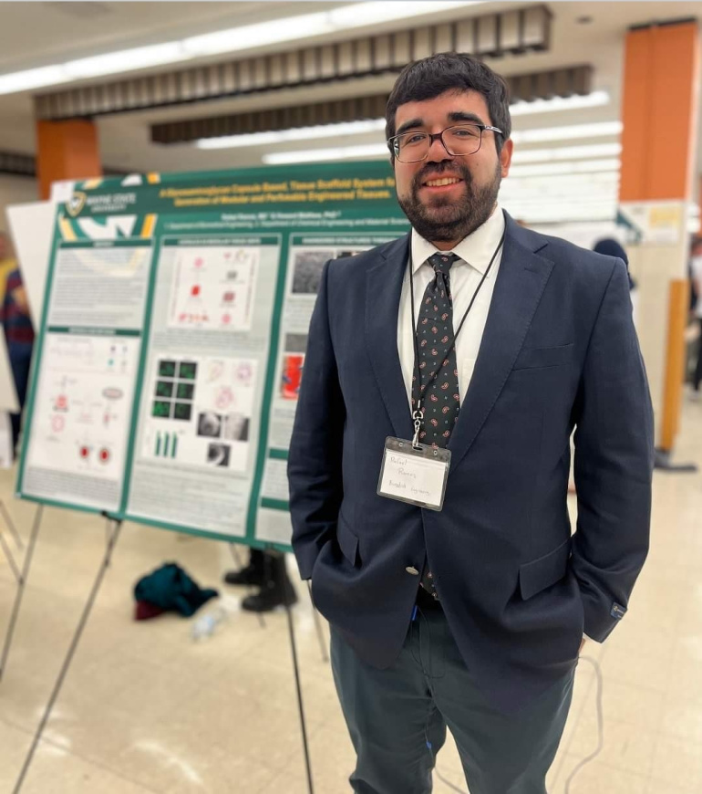 Rafael Ramos poses for a photo in front of his research poster.
