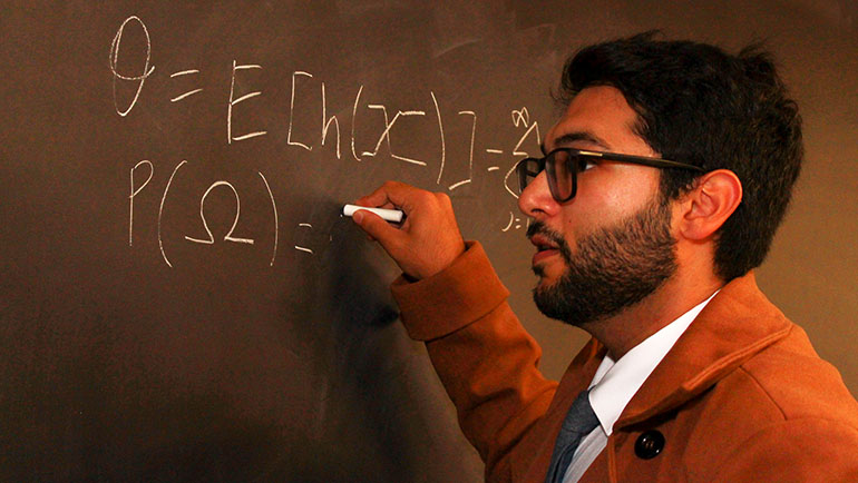 Shawzub Raza, who says “lotteries themselves are completely impractical to mathematicians,” writes out a mathematical formula on a blackboard.