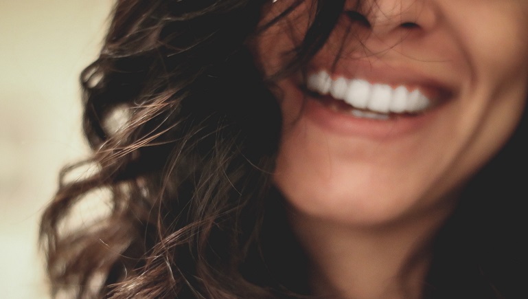 Bottom half of woman's face with curly hair, smiling.