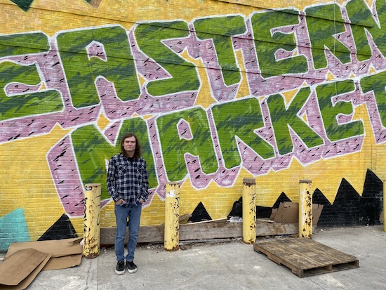 Student Cameron Socha is pictured in front of a mural that reads Eastern Market in Detroit.