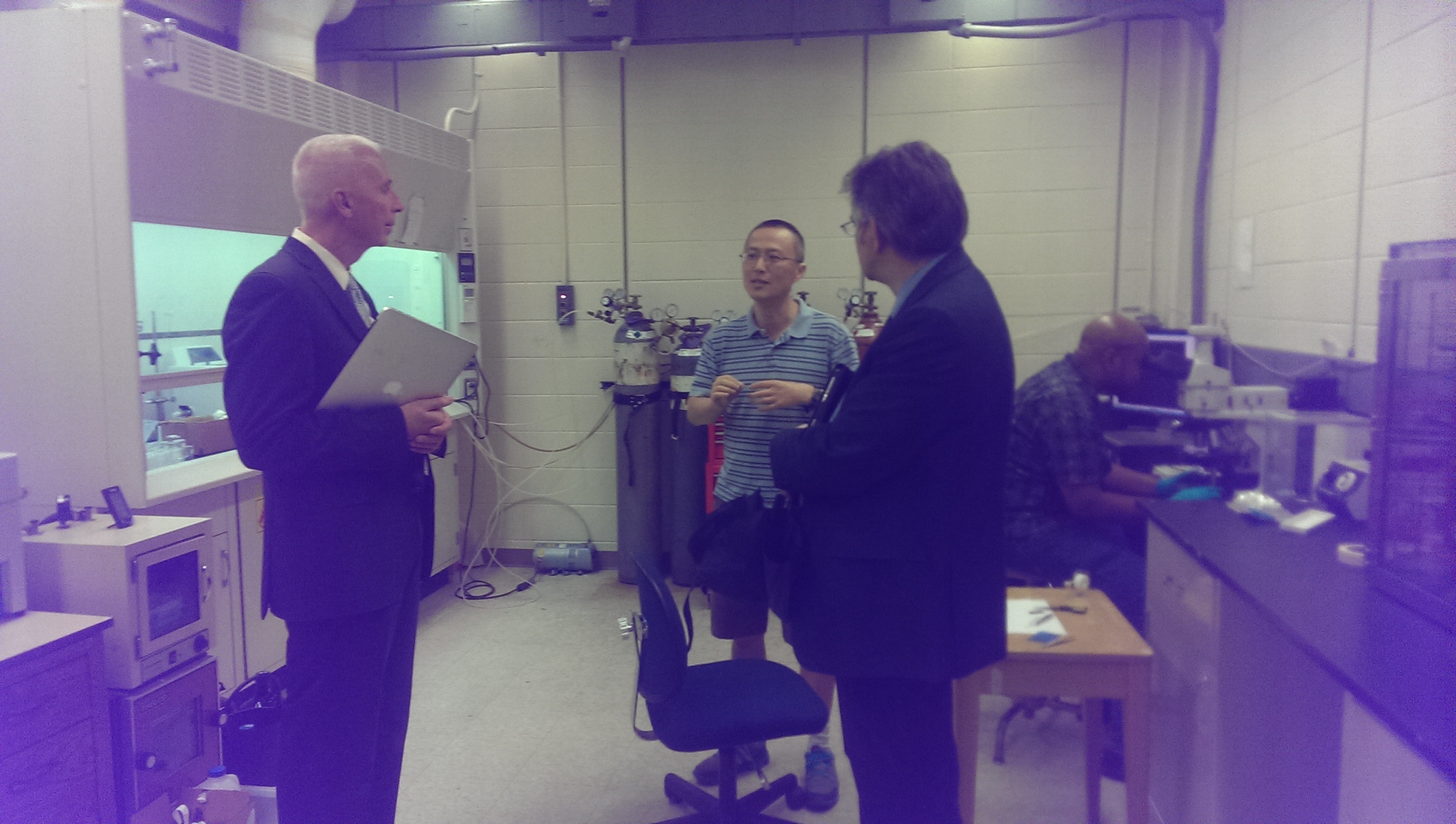 Left to right is VP Lanier, Professor Zhou, Associate Dean and Professor Hoffmann, and using an optical microscope is graduate student Arthur Bowman.