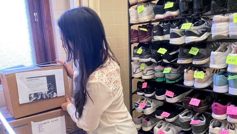 A student organizes a box of donated shoes.