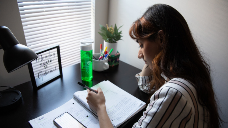 A student studies at a desk in her dorm room.