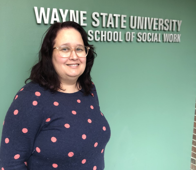 Tomiko Maling poses for a photo in front of the Wayne State School of Social Work sign.