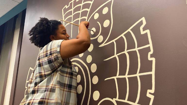 Anaya Crouch paints the Zapotec symbol of Ollin during installation