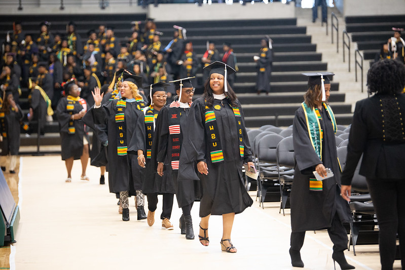 Students wearing graduation caps and gowns from Wayne State University walking in procession in a large building for their graduation ceremony