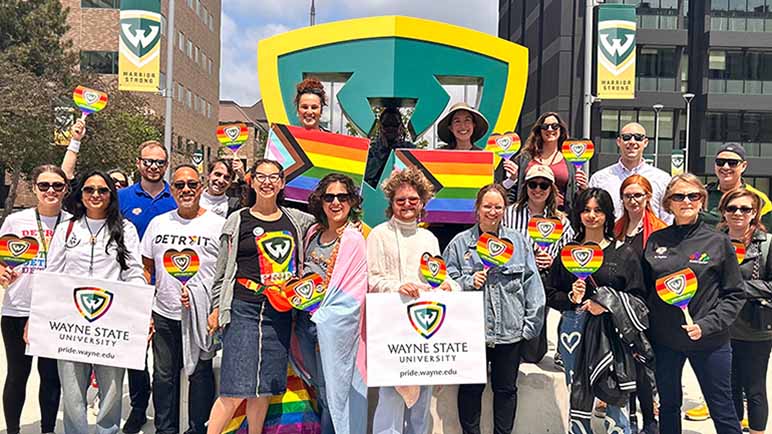 Group of Wayne State faculty, staff and students standing at the Warrior shield on main campus, participating in the annual Stride for Pride event.