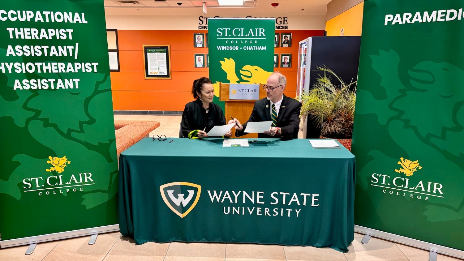 Man and Woman sitting at table exchanging documents to sign