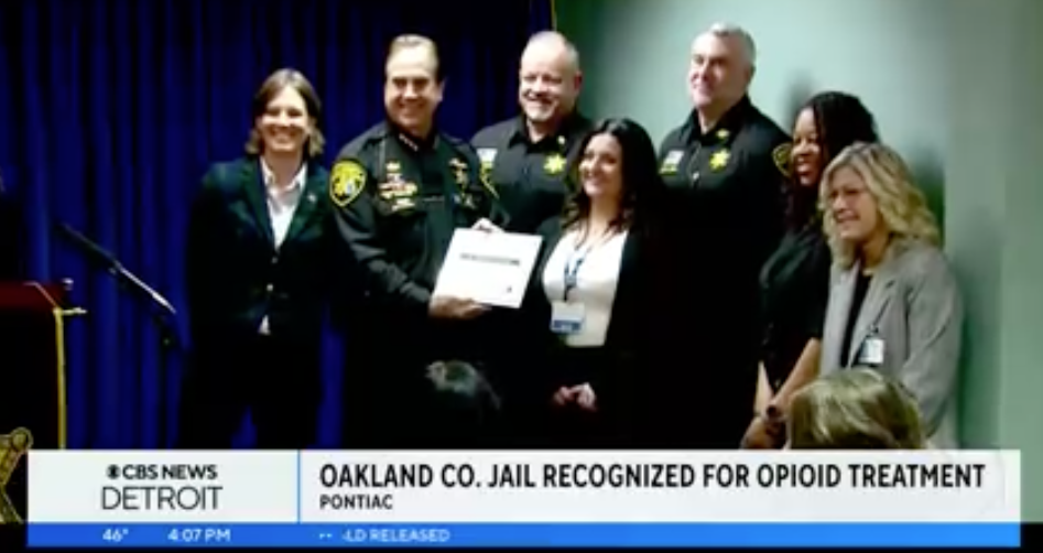 A group photo with Sheriff Bouchard who displays the award of recognition.