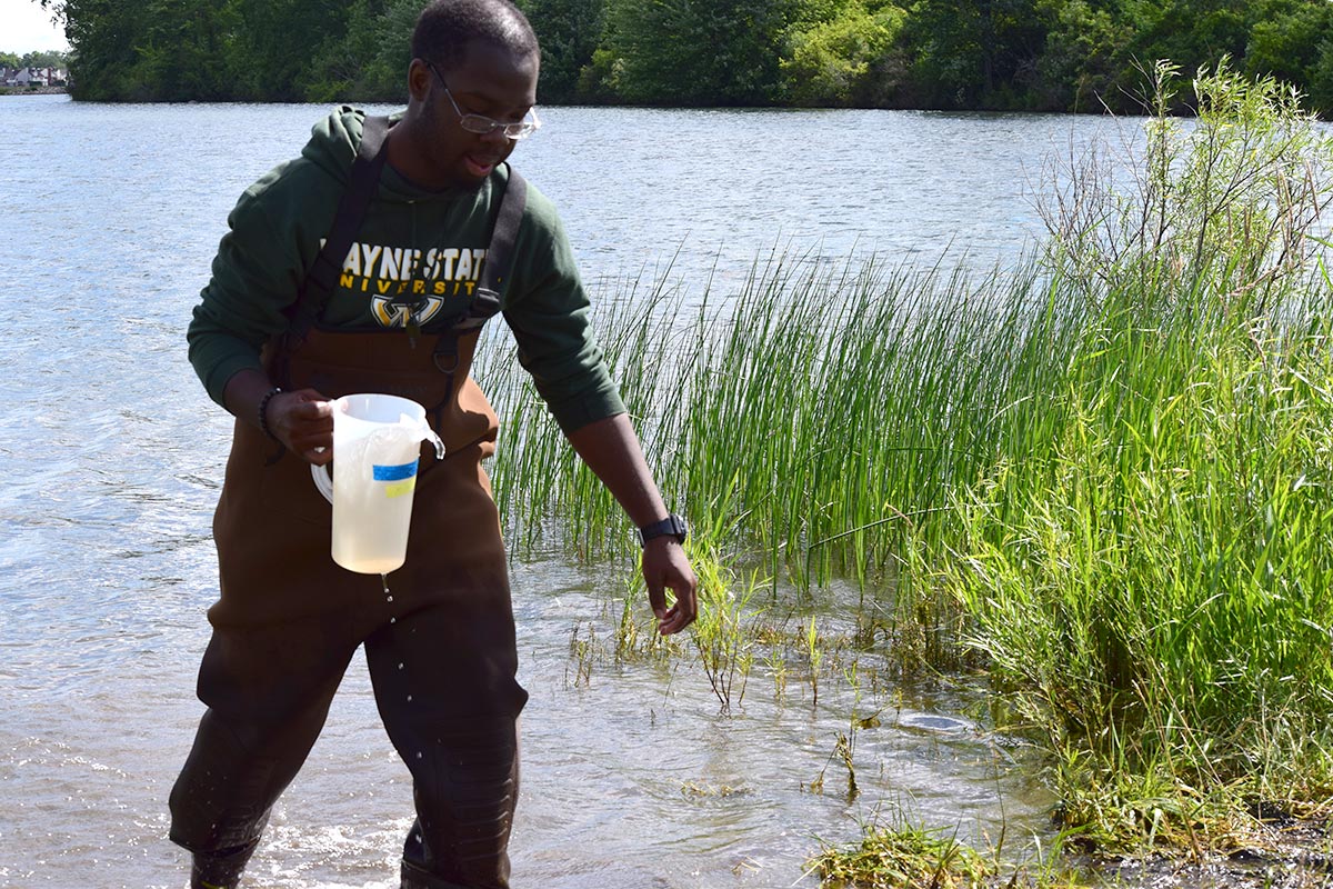 Xavier Walker collects water samples for testing at Belle Isle.